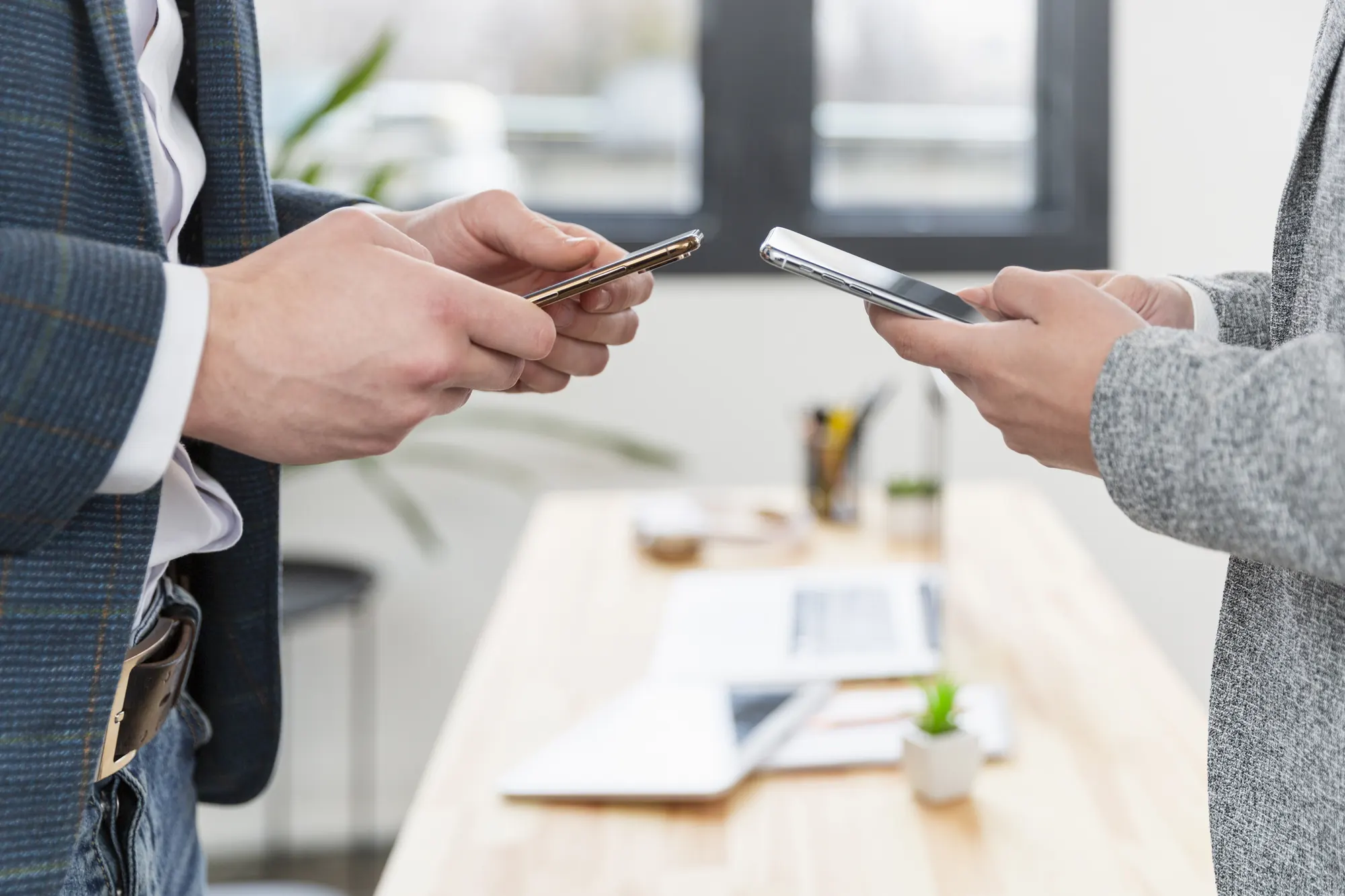 Close-up of two people exchanging contact details on their phones in a modern office