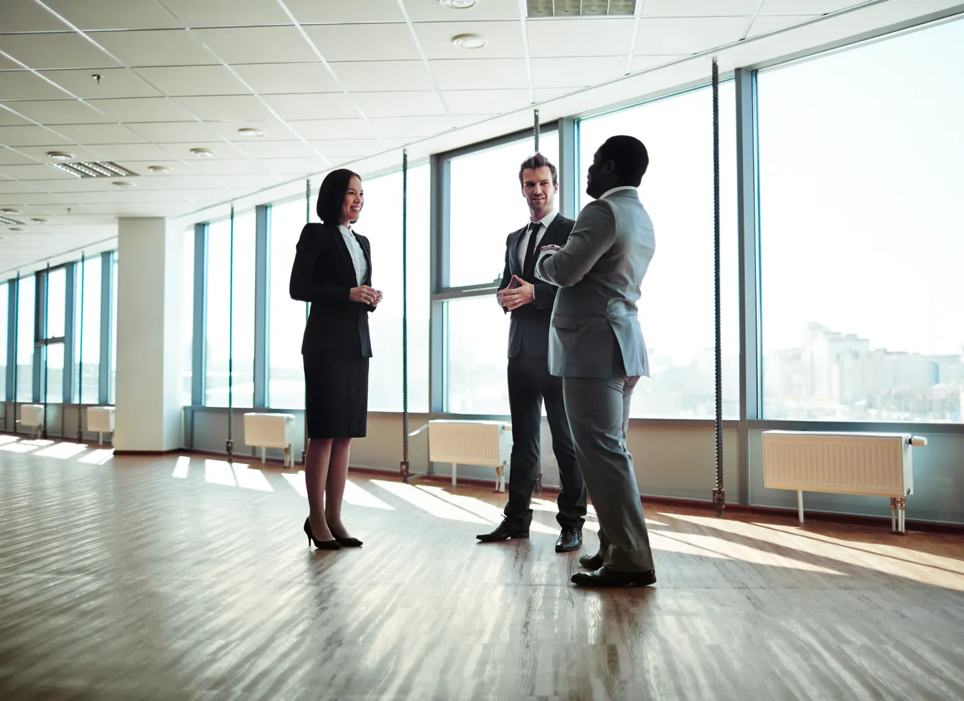 Three business executives in conversation in a bright, modern office space